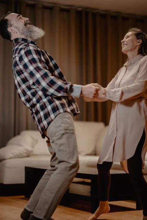 A senior couple dancing together in their living room